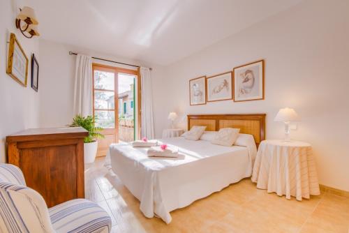 una camera da letto con un grande letto bianco e due sedie di Blau Mari 2 PAX a Sa Ràpita