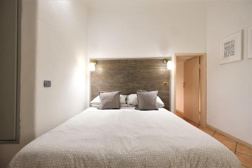 una camera da letto con un letto grande con lenzuola e cuscini bianchi di Wine Apartments Florence Dolcetto a Firenze