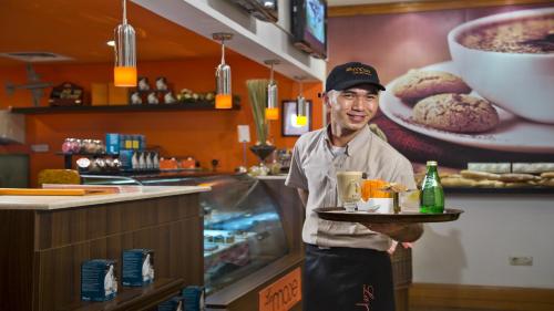 a man holding a tray of food in a restaurant at Holiday Inn Al Khobar by IHG in Al Khobar
