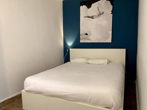 Cama blanca en habitación con pared azul en Paz Apartment, en Lisboa