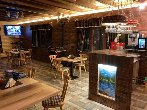 a restaurant with a fireplace in the middle of a room at Căsuța - La Țanc in Martinie