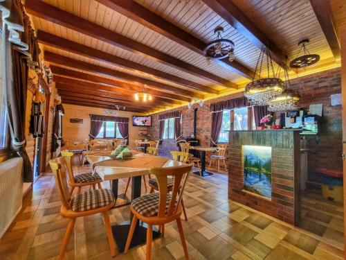a dining room with a wooden table and chairs at Căsuța - La Țanc in Martinie