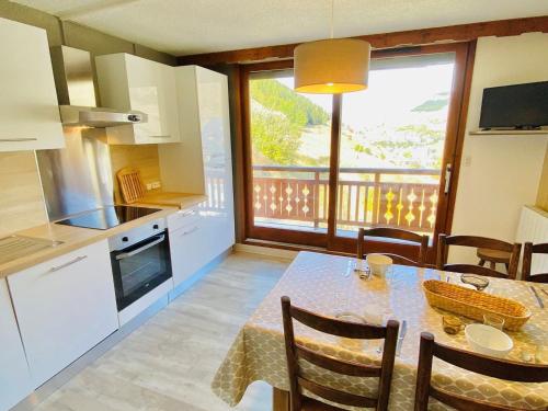 une cuisine avec une table avec des chaises et une salle à manger dans l'établissement Duplex moderne avec balcon, parking, cuisine équipée - FR-1-516-22, à Les Deux Alpes