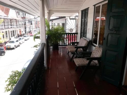 a porch with chairs and a door and a street at Guesthouse AlbergoAlberga in Paramaribo