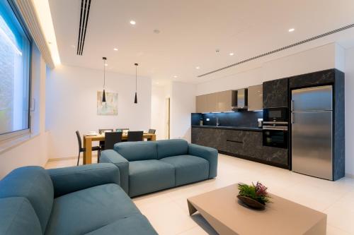 a living room with a blue couch and a kitchen at Cove Seaview Villas - Neptune in Ayia Napa