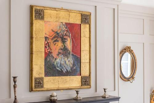a painting of a man on a wall next to a mirror at Fairway - modern and stylish holiday home in Kent