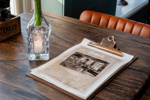 a table with a book and a vase and a bottle at De Watersport Heeg in Heeg