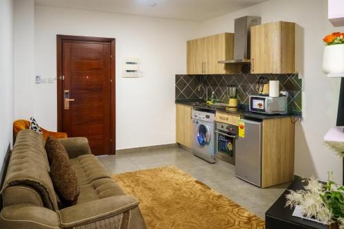 uma sala de estar com um sofá e uma cozinha em OASIS PARK RESIDENCE em East Legon