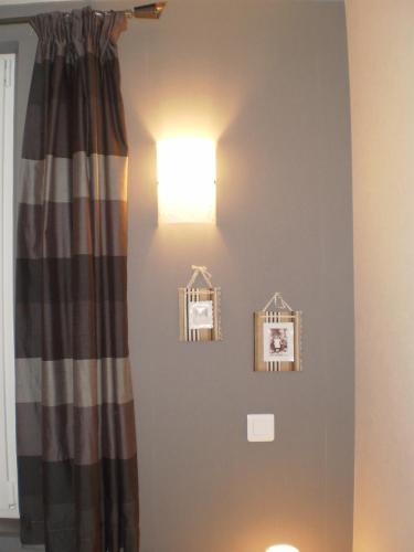 a light on a wall with pictures on it at Chambres d'Hôtes le Clos des Lesses in Fresse-sur-Moselle