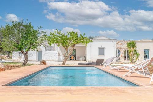 uma piscina com duas cadeiras e uma casa em Bianco Trullo by Raro Villas em Latiano