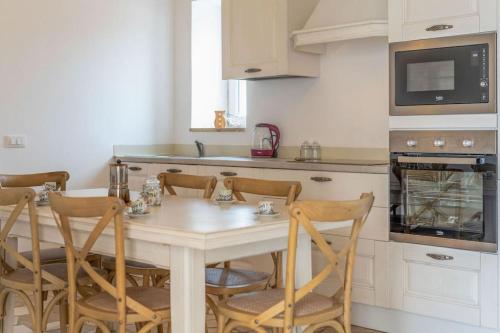 a kitchen with a table with chairs and a microwave at Bianco Trullo by Raro Villas in Latiano