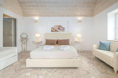 a white bedroom with a bed and a couch at Bianco Trullo by Raro Villas in Latiano