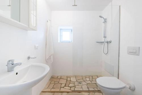 Baño blanco con lavabo y aseo en Bianco Trullo by Raro Villas, en Latiano