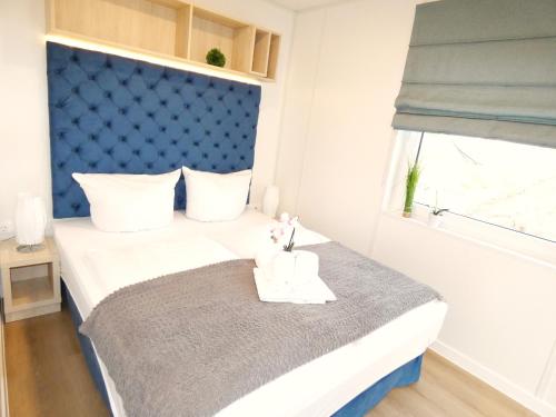 a small bedroom with a bed with a blue headboard at Chalet am See in Wackersdorf