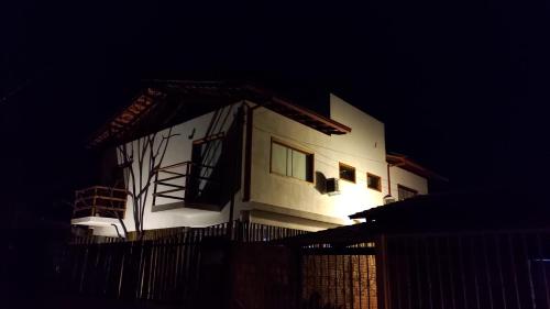 a white house with a fence in front of it at night at Tronco do Ipê Hospedagem in Alto Paraíso de Goiás