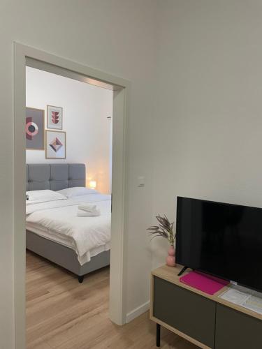 um quarto com uma cama e uma televisão de ecrã plano em Apartments Antini em Solin