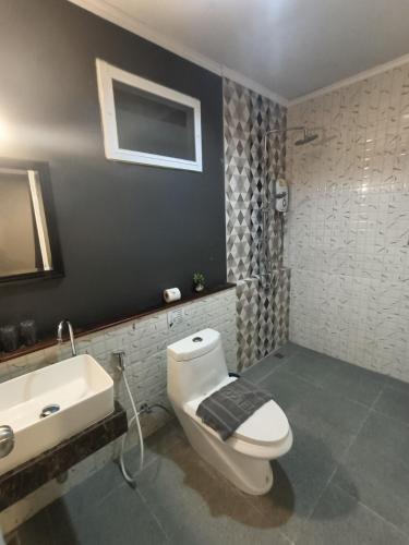 a bathroom with a white toilet and a sink at Aen Guy Boutique Hotel in Sukhothai