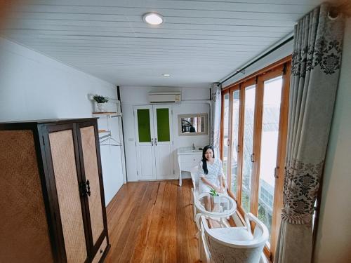 a woman sitting in a room with a window at Aen Guy Boutique Hotel in Sukhothai
