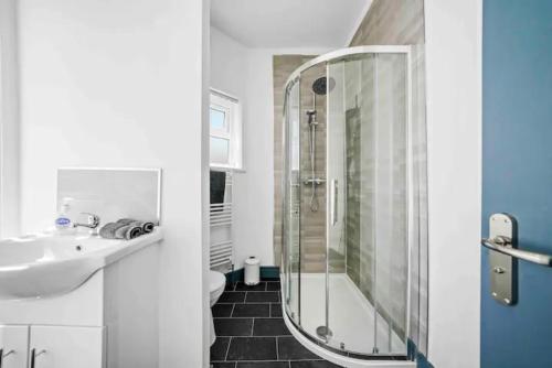 y baño blanco con lavabo y ducha. en Modern Equipped 4 BR House in Central Stoke-Free Parking en Stoke on Trent