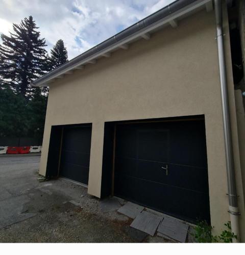 Deux portes de garage sur le côté d'une maison dans l'établissement Bienvenue chez les Trutes, à Modane