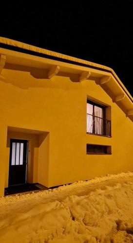 Casa amarilla con 2 ventanas y balcón. en Bienvenue chez les Trutes, en Modane