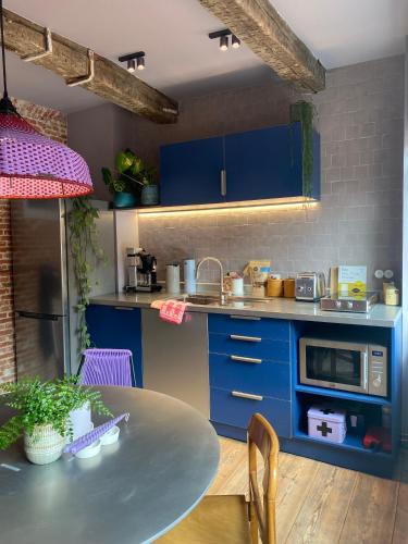 a kitchen with blue cabinets and a table at Bed & Binnekyk in Mechelen
