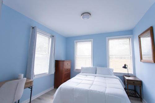 a blue bedroom with a bed and a desk and windows at Central & Comfortable Home Walk to the Beach! in Jacksonville Beach
