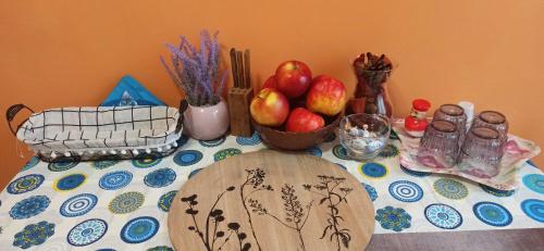 a table with a bowl of apples and other items on it at Karancs Apartman Salgótarján in Salgótarján