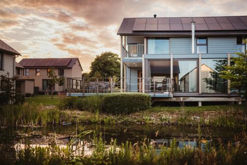 a house with a pond in front of it at Golden Lakes Village Ardennes in Boussu-lez-Walcourt