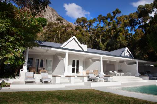 a white house with chairs and a swimming pool at La Petite Ferme in Franschhoek