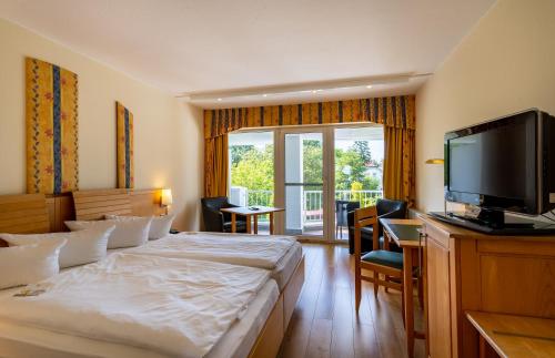 a hotel room with two beds and a flat screen tv at Seehotel Fährhaus in Bad Zwischenahn