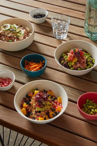 four bowls of food on a wooden table at Combo Milano in Milan