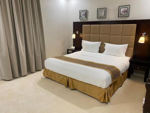 une chambre avec un grand lit avec des draps et des oreillers blancs dans l'établissement جلنار الشرق للشقق المخدومة, à Djeddah