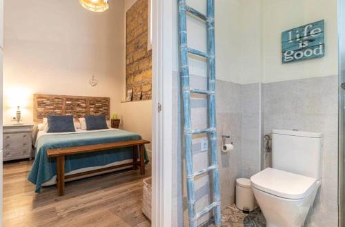 1 dormitorio con cama, aseo y escalera en Loft Bodega San Blas con porche y parking, en Jerez de la Frontera