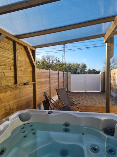 a hot tub in a backyard with a wooden fence at A Fleur de Spa : Maison chaleureuse avec spa privatif et billard. in Coulogne
