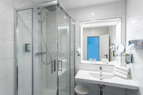 a white bathroom with a sink and a shower at Seehotel Fährhaus in Bad Zwischenahn