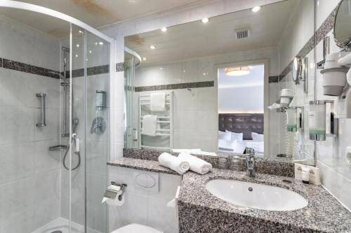 La salle de bains est pourvue d'un lavabo, d'une douche et d'un miroir. dans l'établissement Seehotel Fährhaus, à Bad Zwischenahn