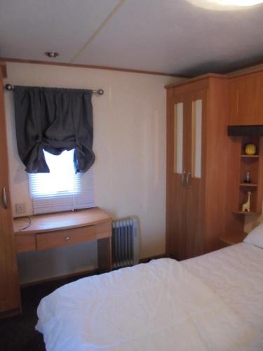 a bedroom with a bed and a window at 6 Berth heated on The Chase Brisbane in Ingoldmells