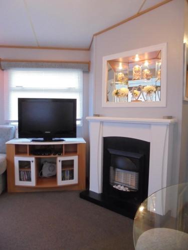 a living room with a television and a fireplace at 6 Berth heated on The Chase Brisbane in Ingoldmells