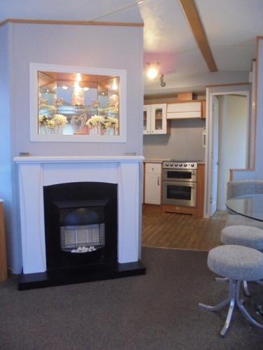 a living room with a fireplace and a kitchen at 6 Berth heated on The Chase Brisbane in Ingoldmells