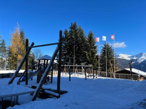 a playground in the snow with two canadian flags at Cosy studio for 5 near ski lift, HAMEAU D2 in Les Collons