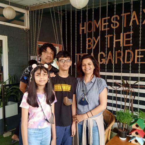a family standing in front of a house by the gate at Homestay by the Tea Garden Dibrugarh in Dibrugarh