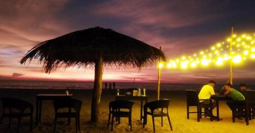 a couple sitting at a bar on the beach at night at Marari diya homestay in Mararikulam