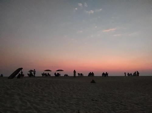 a group of people on the beach at sunset at Marari diya homestay in Mararikulam
