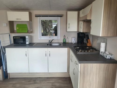 a small kitchen with white cabinets and a sink at Märchencamping in Stuhr