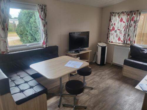 a small living room with a table and a tv at Märchencamping in Stuhr