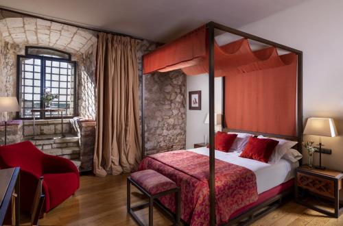 a bedroom with a canopy bed with a red blanket at Parador de Alarcón in Alarcón