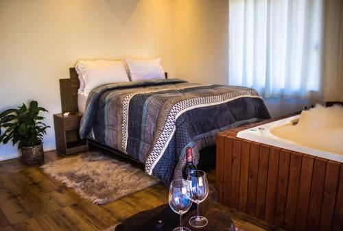 a bedroom with a bed and a tub with two wine glasses at Império Cabanas in Urubici