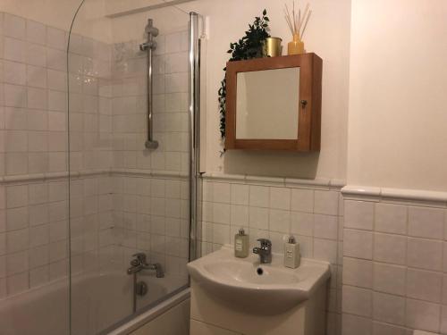 a bathroom with a sink and a shower with a mirror at Cute flat in Whitechapel in London