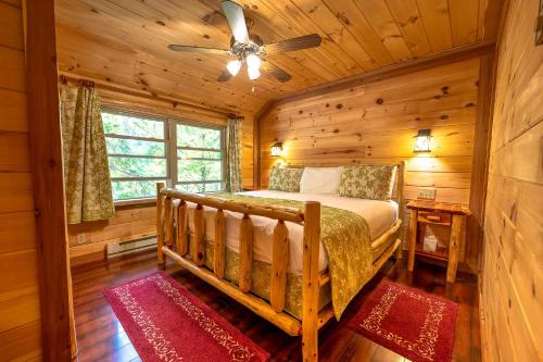 ein Schlafzimmer mit einem Bett in einer Blockhütte in der Unterkunft Motel Long Lake and Cottages in Long Lake
